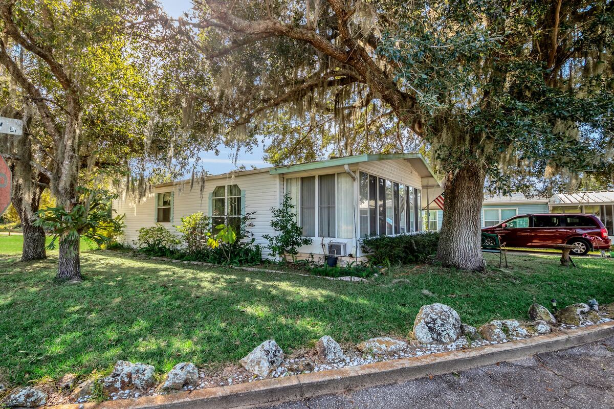 Manufactured home beneath mature trees at Hide-A-Way Harbor